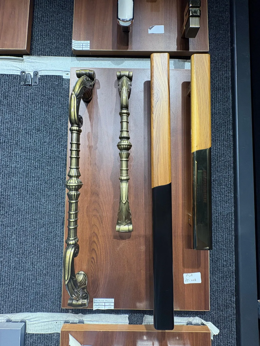 Long wardrobe pull handles in metal finishes displayed on a wall rail