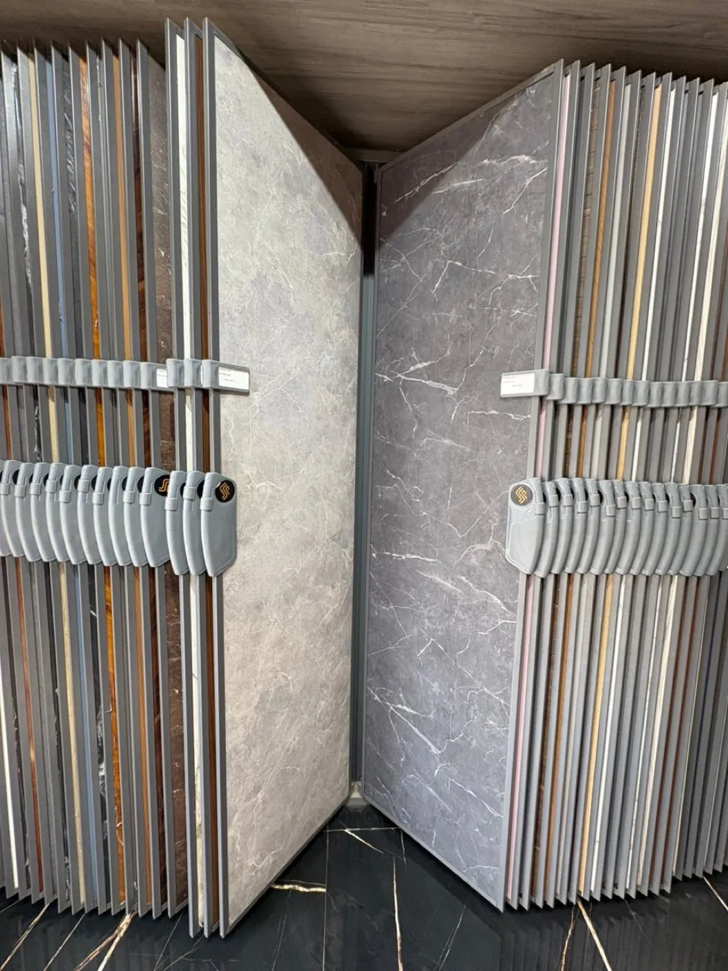 A showroom rack of large marble- and wood-look laminate sheets on swing-out panels